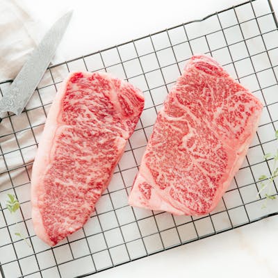 Frozen raw wagyu steaks sit on a wire oven tray.