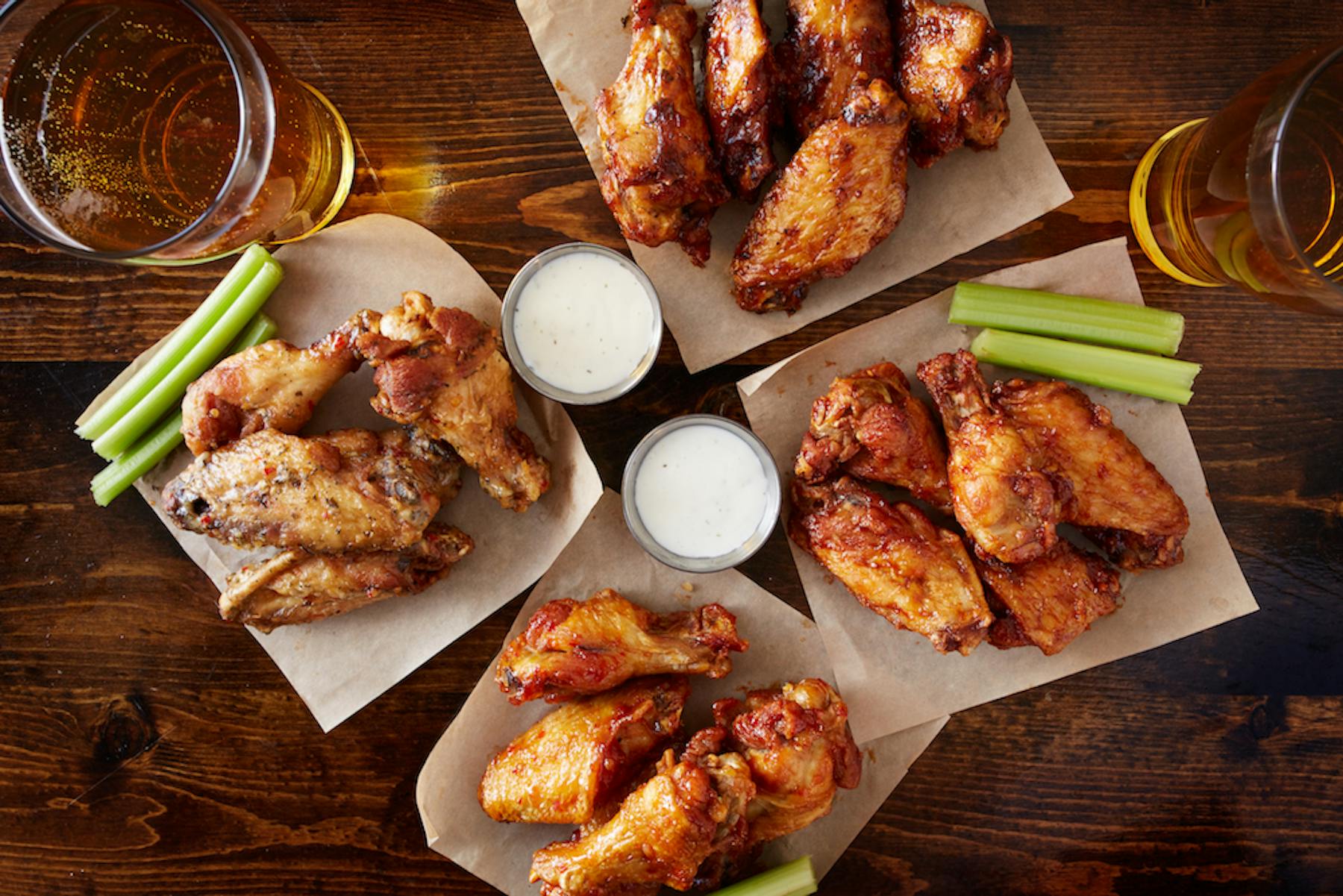 Image of fried chicken wings with bbq sauce and a beer.