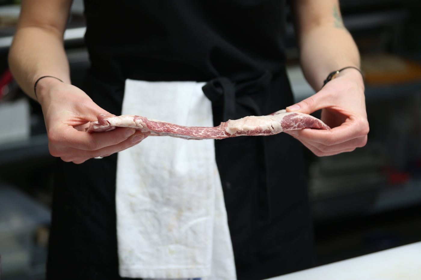 Chef holding a raw Iberico pork Secreto cut, showing marbling and thickness